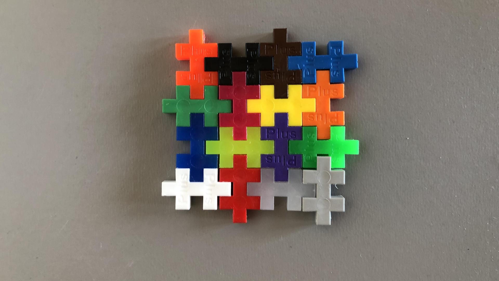 Bunte Puzzleteile, die ineinander stecken und eine Quadrat ergeben.